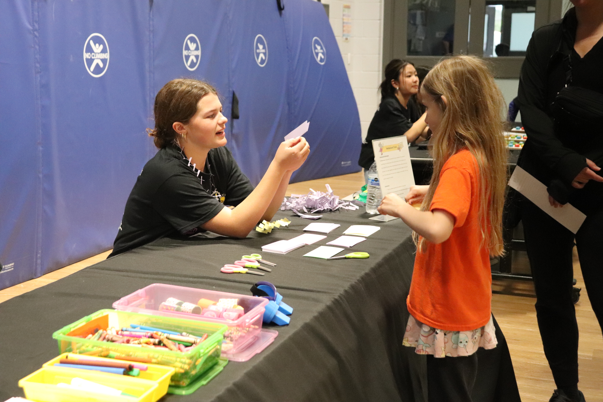 SiS volunteer helping a young student with a hands-on activity